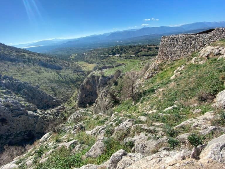 Scenic mountain landscape with ancient ruins and lush greenery in the background.