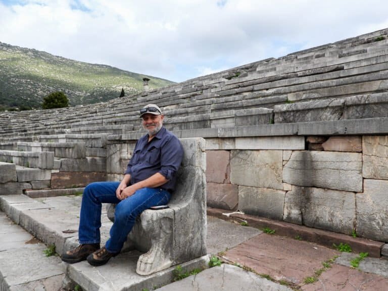 Ancient Greek theater with a seated man enjoying the historic site.