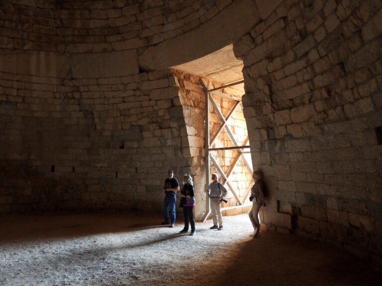 Visitors exploring an ancient stone structure with large arch and wooden scaffolding.