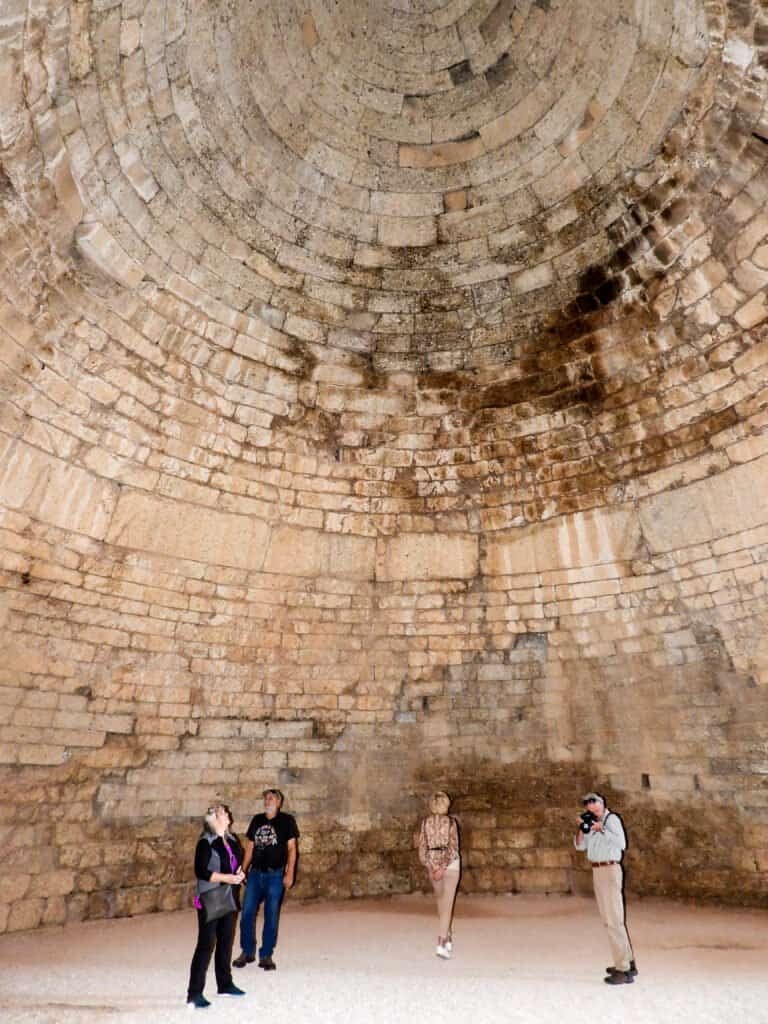 Interior view of a large ancient underground brick structure with visitors exploring.