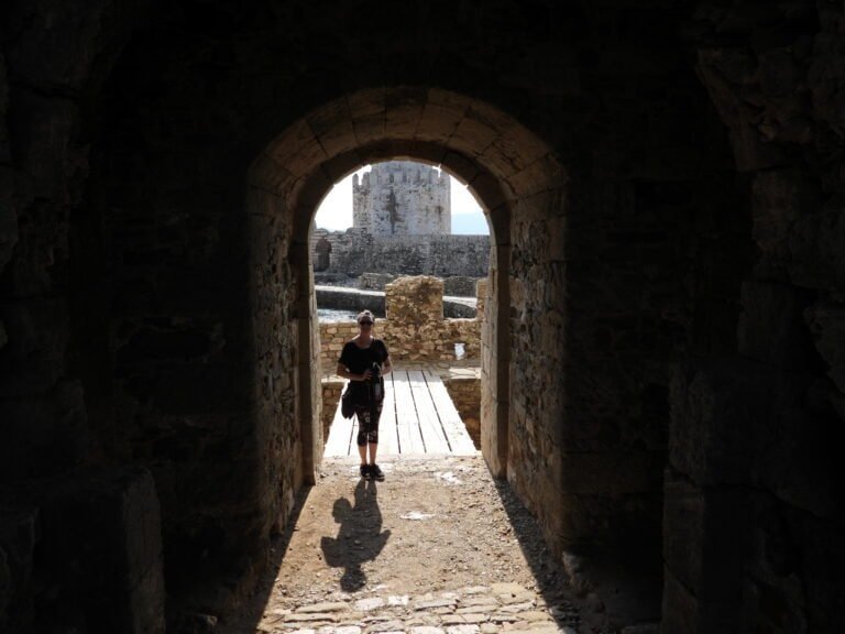 Child walking through castle archway with tower in background.