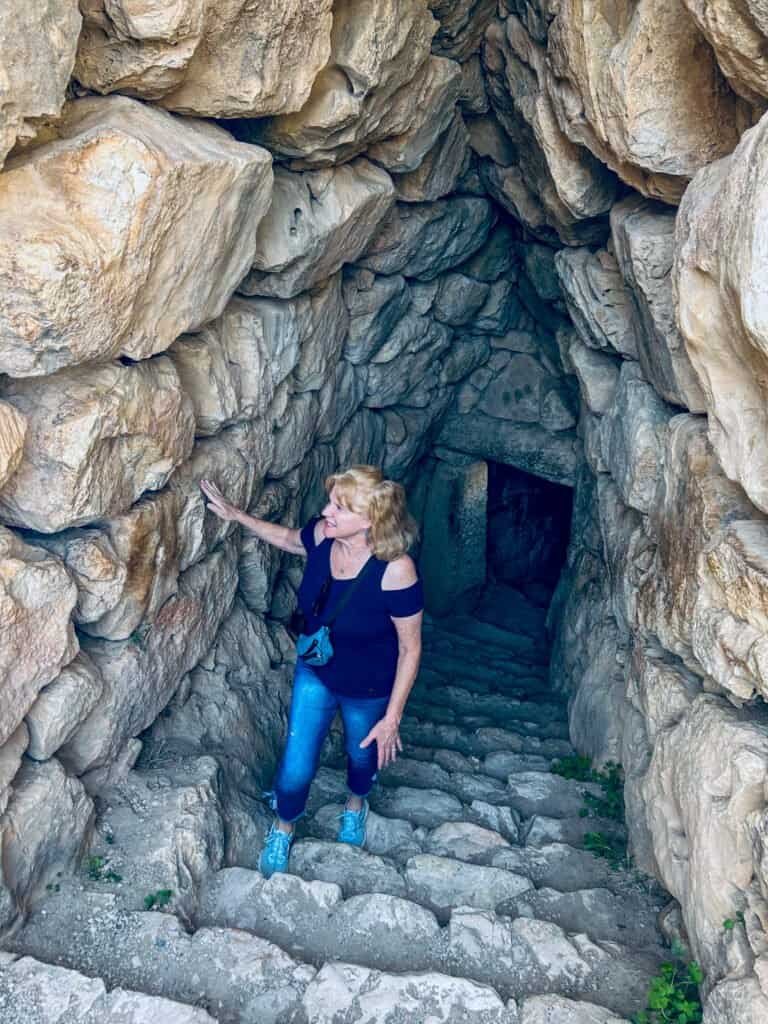 Woman exploring a historic stone cave with stairs and rocky walls.