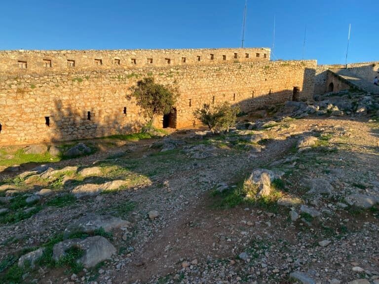 Ancient fortress wall at Odyssey Academy with rocky terrain.