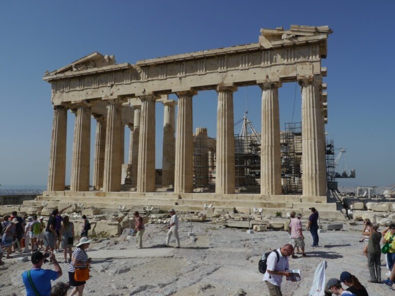 Parthenon temple on Athens Acropolis with tourists visiting.