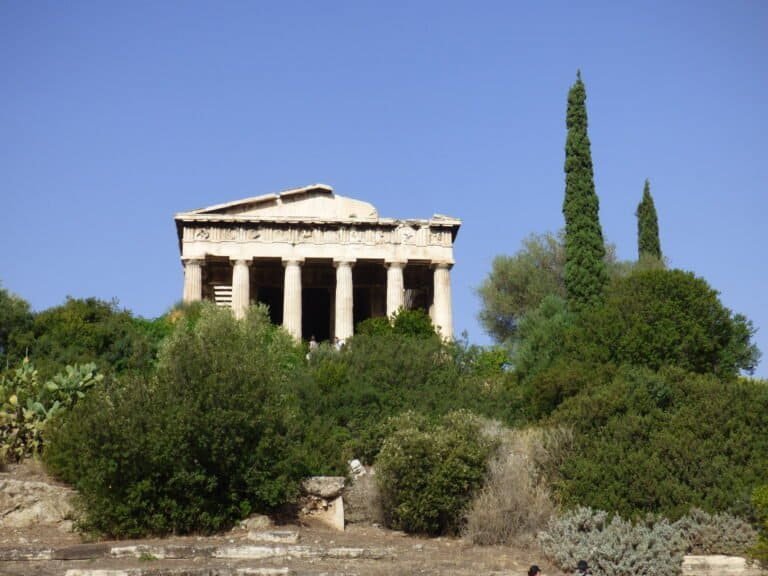 Iconic ancient Greek temple on Acropolis with lush greenery and clear blue sky.
