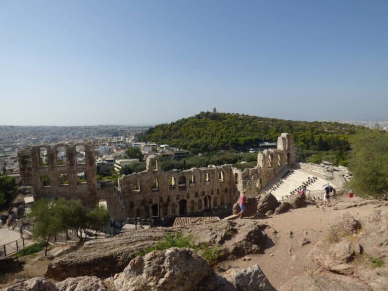 Ancient amphitheater ruins overlooking Athens with cityscape background.
