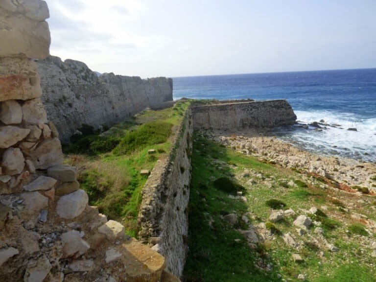 Ancient fortress walls overlooking the ocean, showcasing historical architecture and scenic seaside.