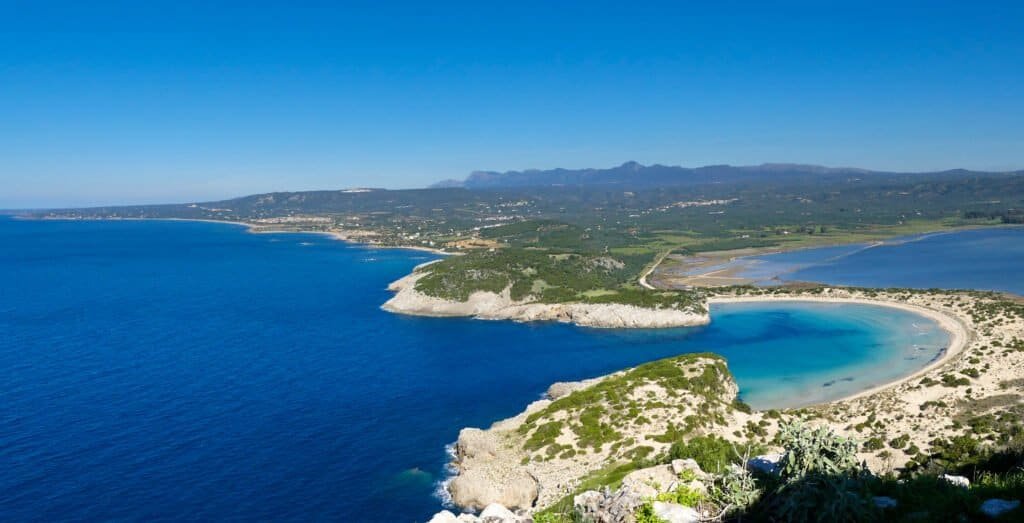 Scenic view of the coastline with clear blue waters and lush green hills.