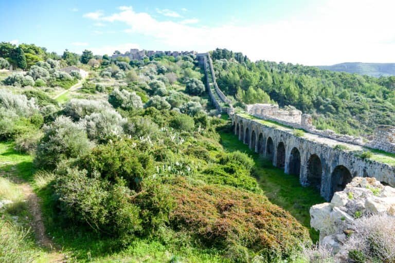Ancient Roman aqueduct in lush green landscape, Odyssey Academy.