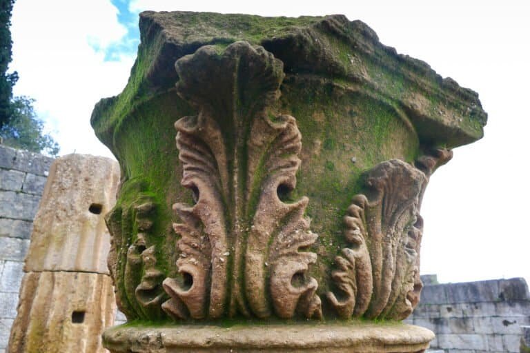 Ornate Corinthian column capital with detailed acanthus leaf carvings, showcasing classical Greek ar.