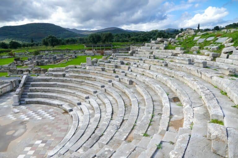 Ancient stone amphitheater with scenic mountain backdrop.