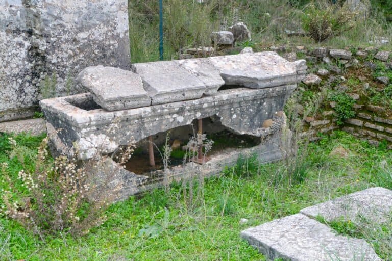 Ancient stone water fountain with multiple basins at Odyssey Academy, showcasing historical architec.