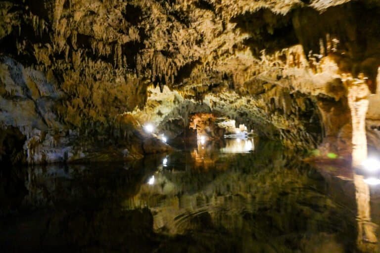 Underground cave with stalactites and stalagmites illuminated for exploration.