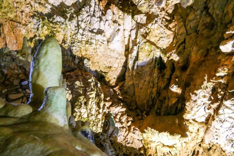 Cave interior featuring stalactites and stalagmites illuminated for exploration.