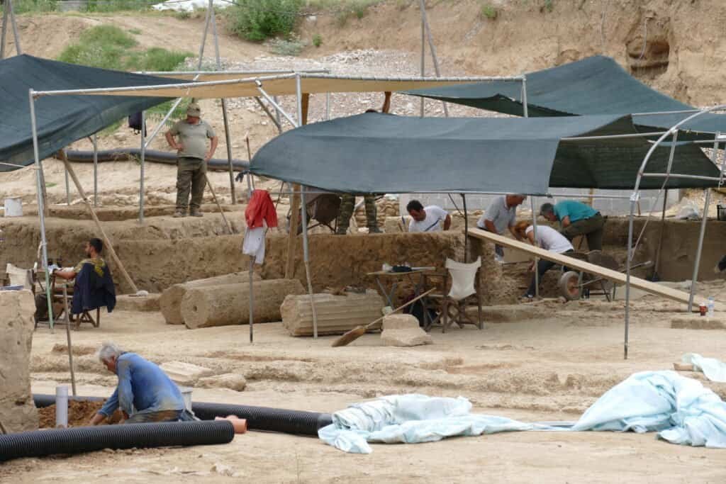 Archaeologists working at an excavation site with ancient artifacts and tools.