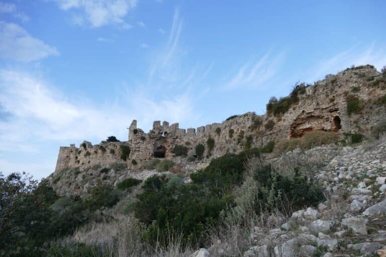 Ruins of an old castle situated on a hillside with scenic sky background.