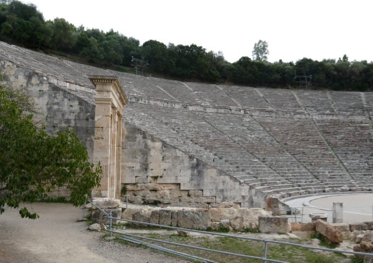 Historic Greek amphitheater with stone seating and classical architecture.