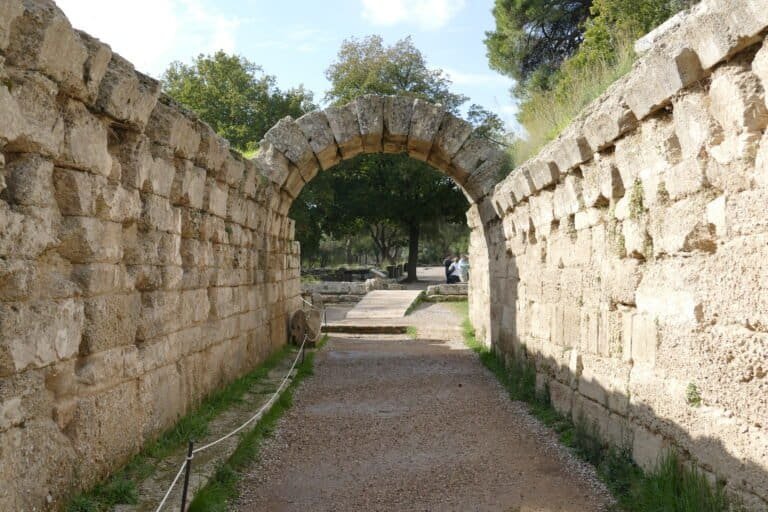Historic stone archway at Odyssey Academy, surrounded by greenery and trees.