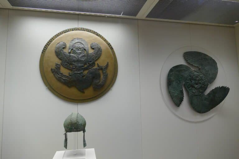 Ancient Asian artifacts including a bronze dragon medallion and a carved stone sculpture showcased a.