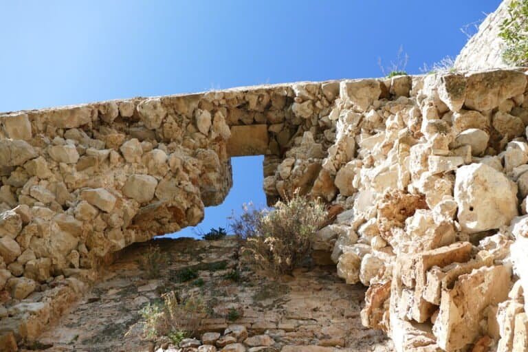 Ancient stone archway with a small window, part of historic ruins in Greece.