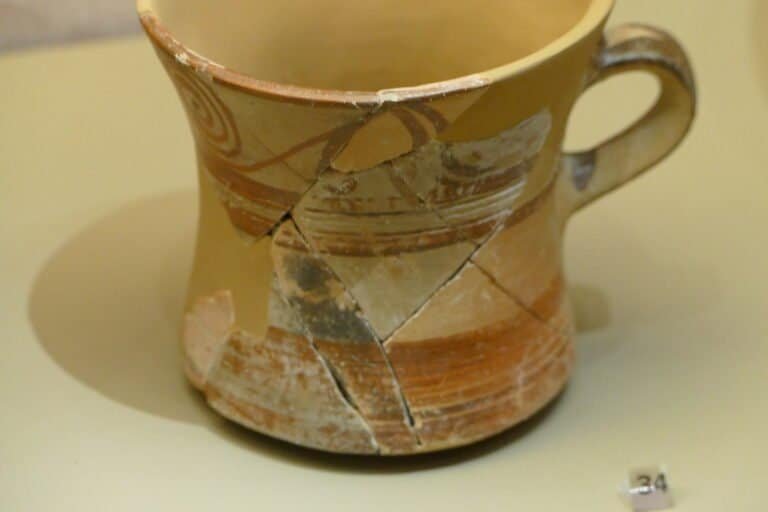 Ancient Greek pottery fragment with painted geometric patterns and signs of age.