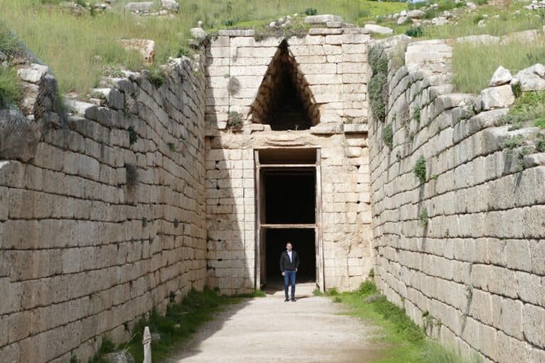 Historic stone entrance at Odyssey Academy with lush green surroundings.