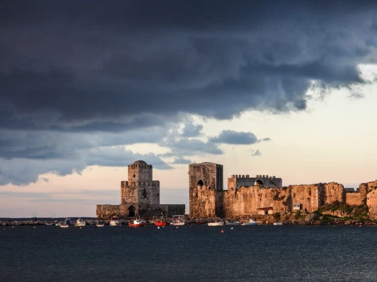 Historic castle ruins on the coast with dark stormy clouds overhead.